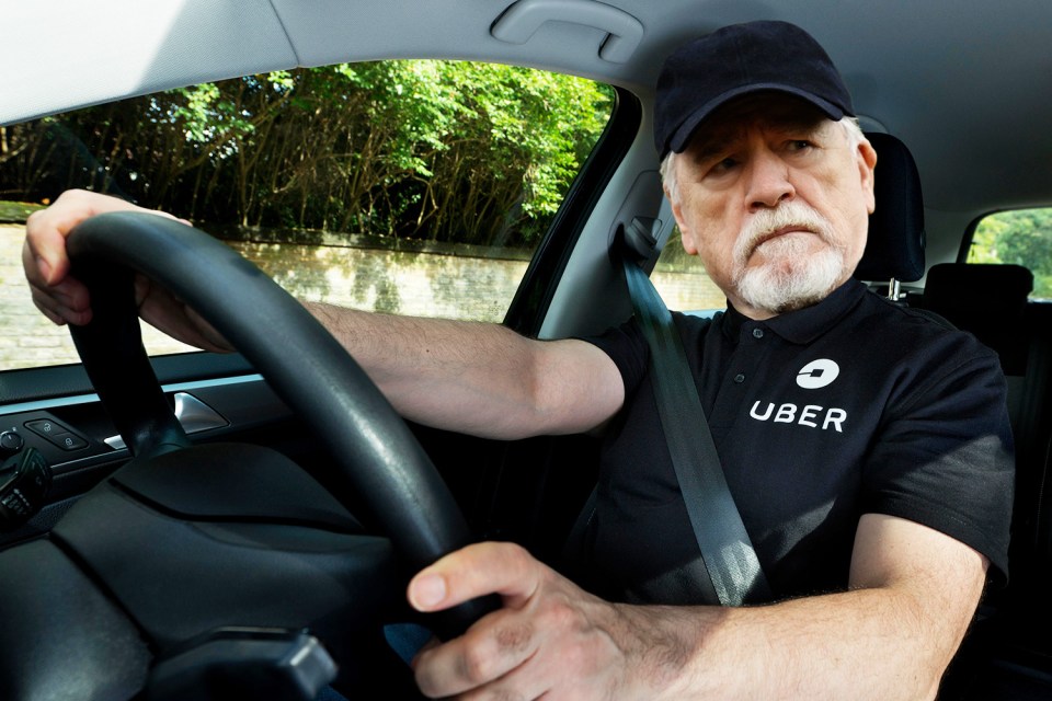 a man wearing an uber shirt is driving a car