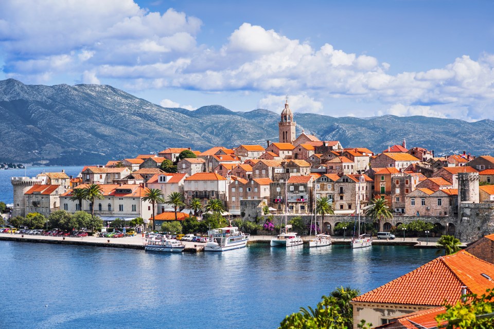 boats are docked in front of a small town with mountains in the background