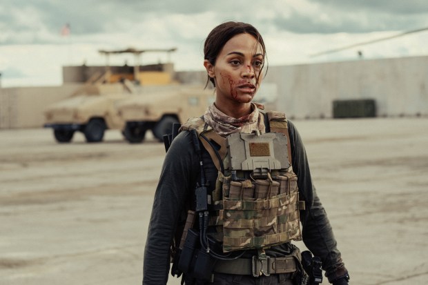 a woman in a military uniform is standing in front of a military vehicle