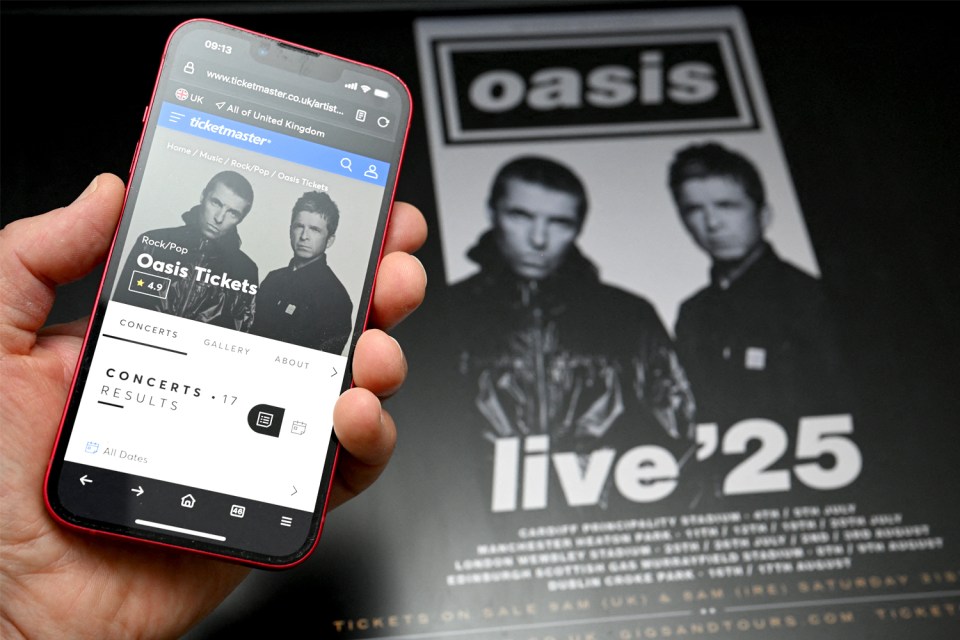 a person is holding a cell phone in front of an oasis poster