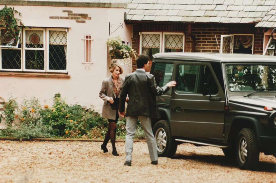 a man and a woman standing in front of a car