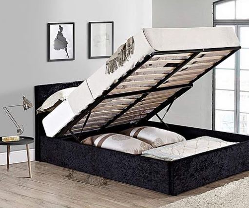 a black ottoman bed with the lid open in a bedroom .