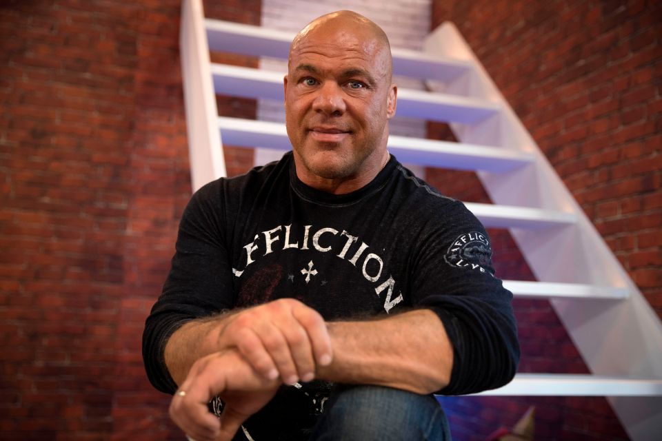 a man wearing a black affliction shirt sits on a set of stairs