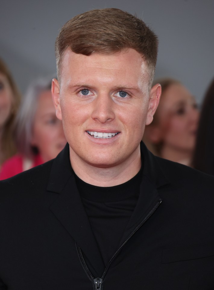 a man in a black jacket smiles for the camera