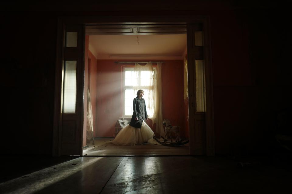 a woman in a white dress is standing in a dark room