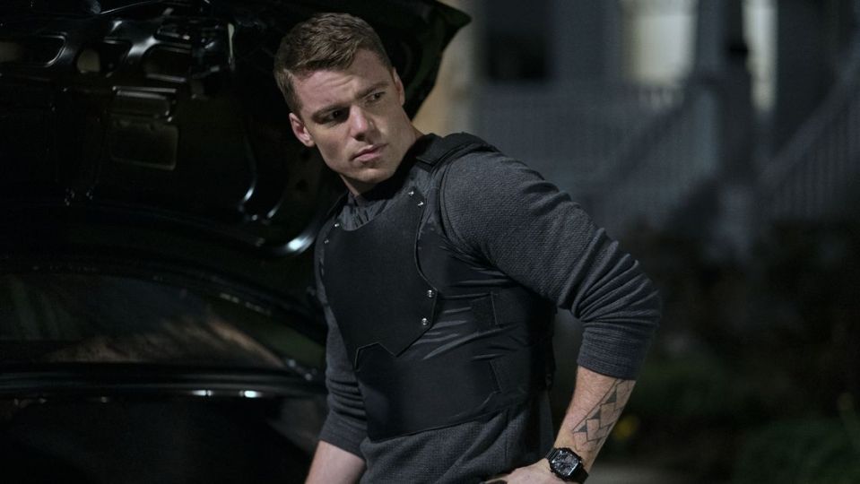 a man with a tattoo on his arm is wearing a black vest