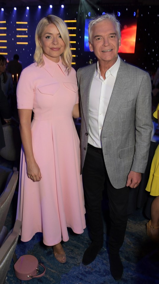 a woman in a pink dress stands next to a man in a suit