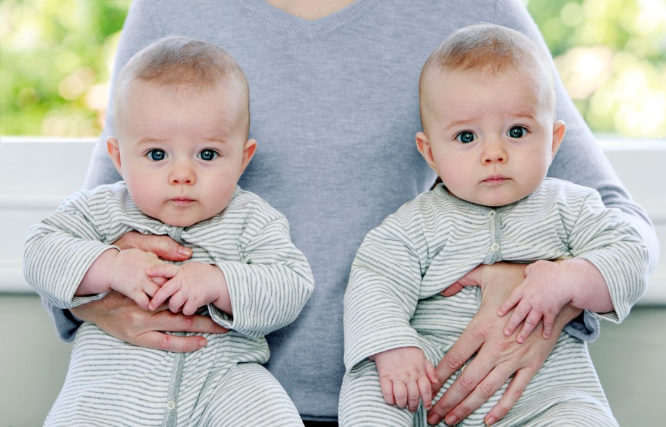 a woman is holding two babies in her arms