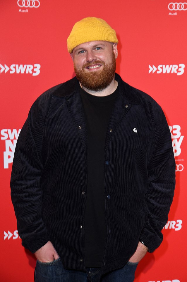 a man wearing a yellow hat and a black jacket stands in front of a red background that says swr3