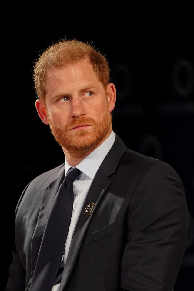 a man with a beard wears a black suit and tie