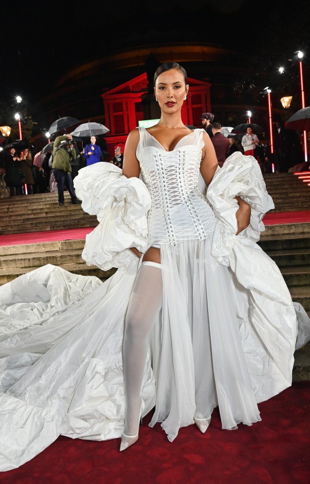 a woman in a white dress is standing on a red carpet