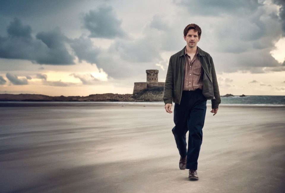 a man walking on a beach with a tower in the background