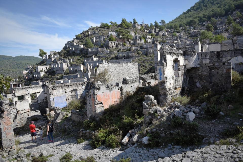 a man in a red shirt stands in front of a ruined building