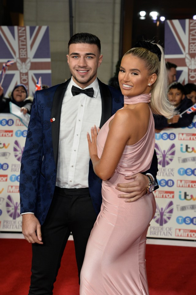 a man in a tuxedo and a woman in a pink dress pose on the red carpet