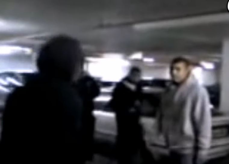 a group of people are standing in a parking garage .