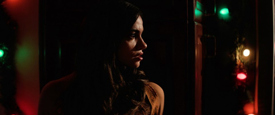 a woman in a dark room with christmas lights behind her