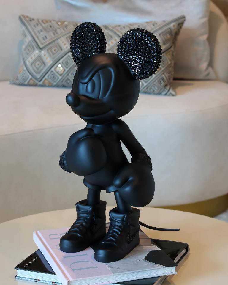 a black mickey mouse figurine sits on top of a stack of books