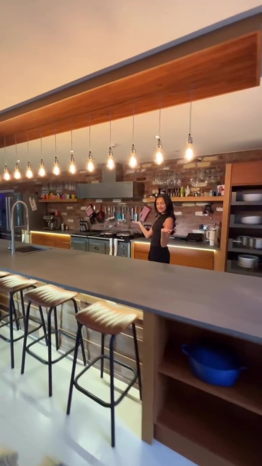 a woman stands in a kitchen holding a cutting board