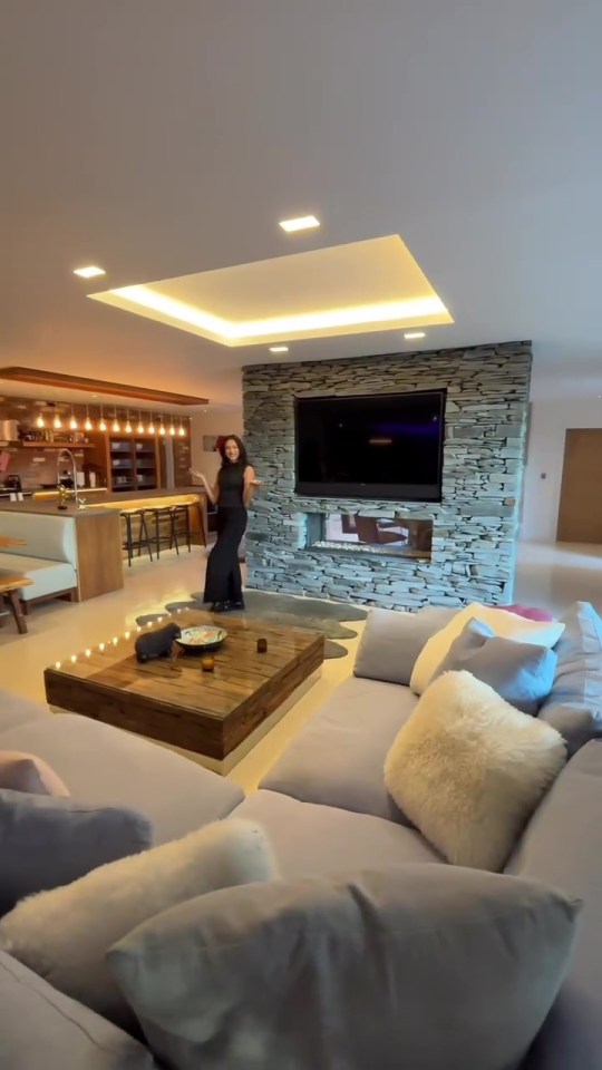 a woman in a black dress is standing in a living room