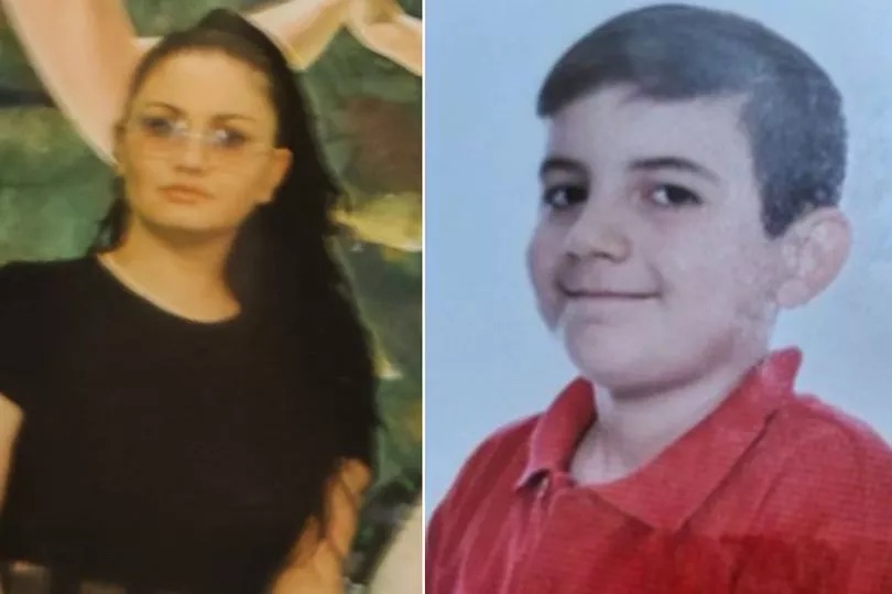 a woman and a boy are posing for a picture together . the boy is wearing a red shirt .