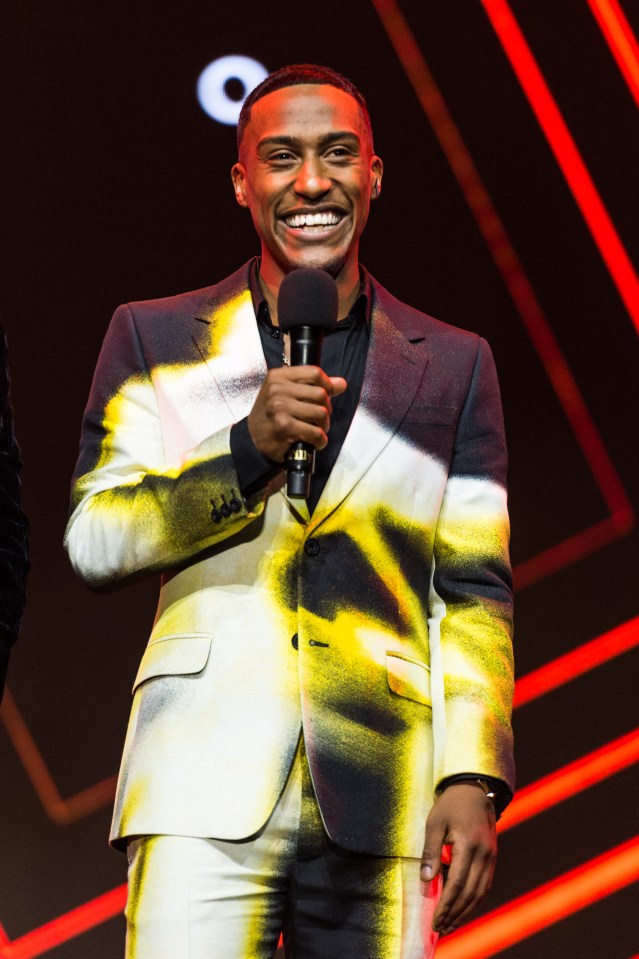 a man in a suit is holding a microphone and smiling