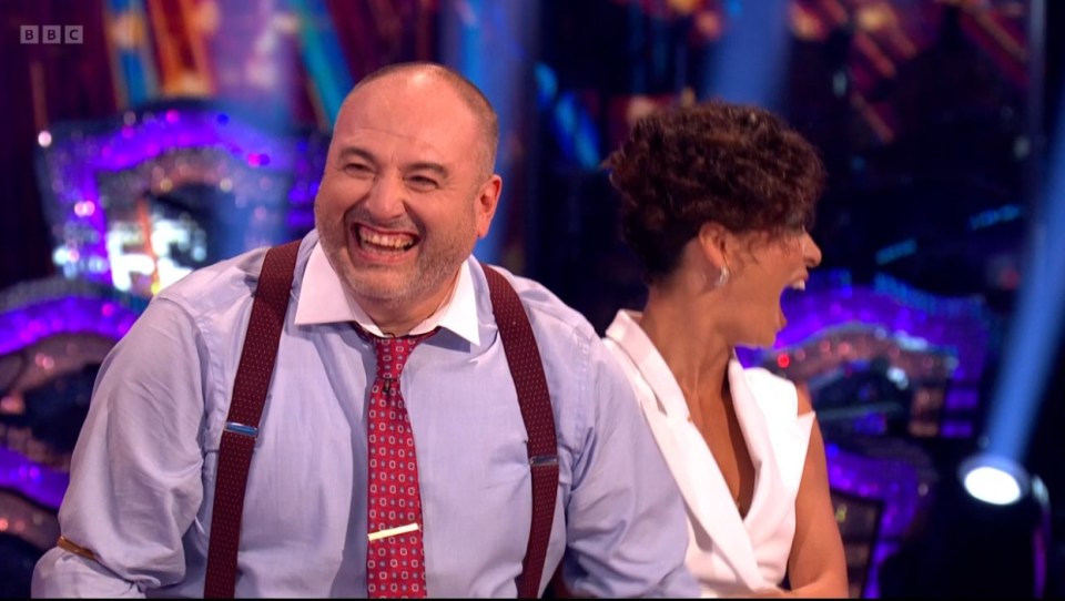 a man wearing suspenders and a tie is laughing next to a woman