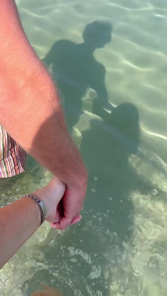 The couple held hands as they waded in the crystal-clear waters