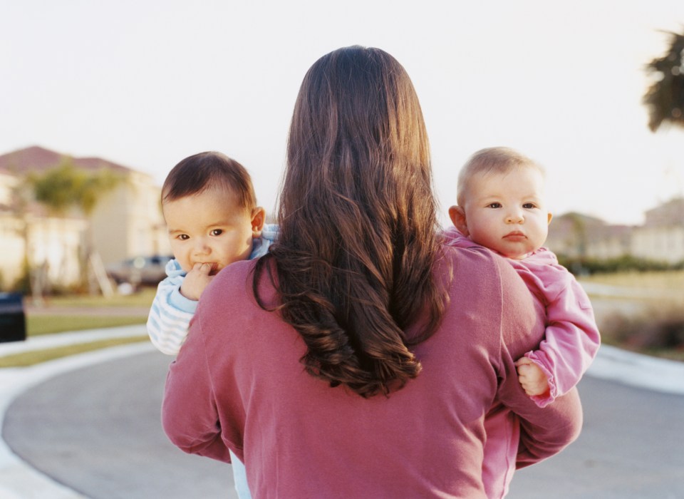 a woman in a pink shirt is holding two babies