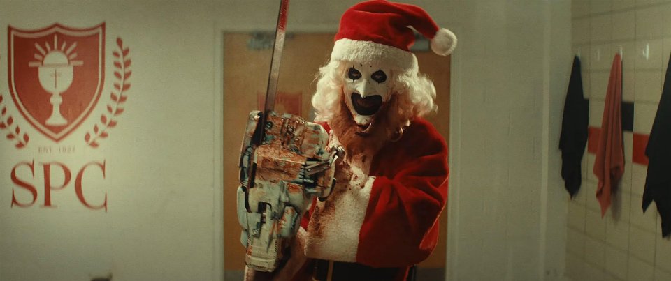 a person dressed as santa claus holding a chainsaw in front of a sign that says spc