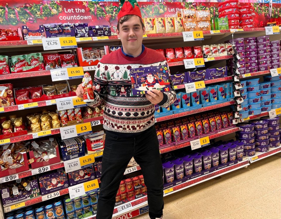 a man in a christmas sweater holds a box of cadbury chocolates