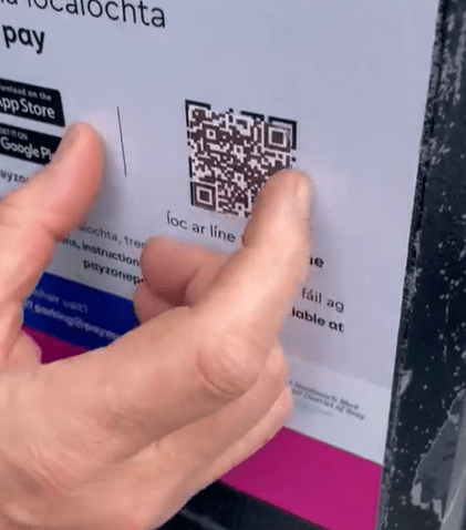 a person is touching a qr code on a sign