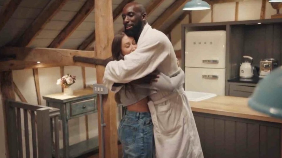 a man in a robe is hugging a woman in a kitchen with a smeg refrigerator in the background