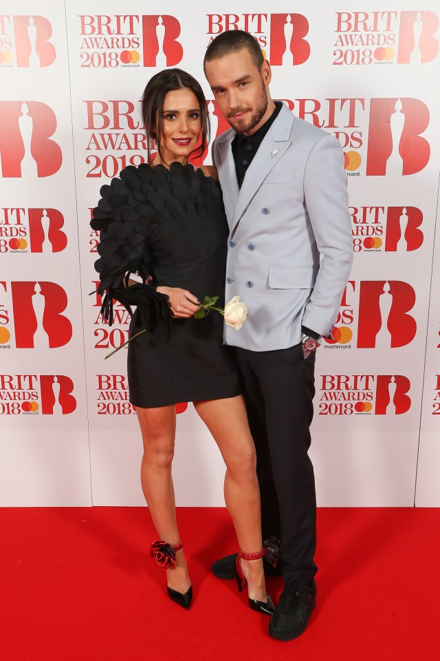 a couple standing on a red carpet that says brit awards 2018