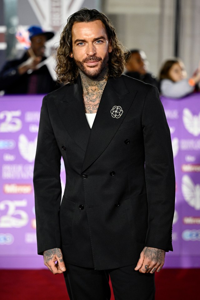 a man in a black suit is standing on a red carpet