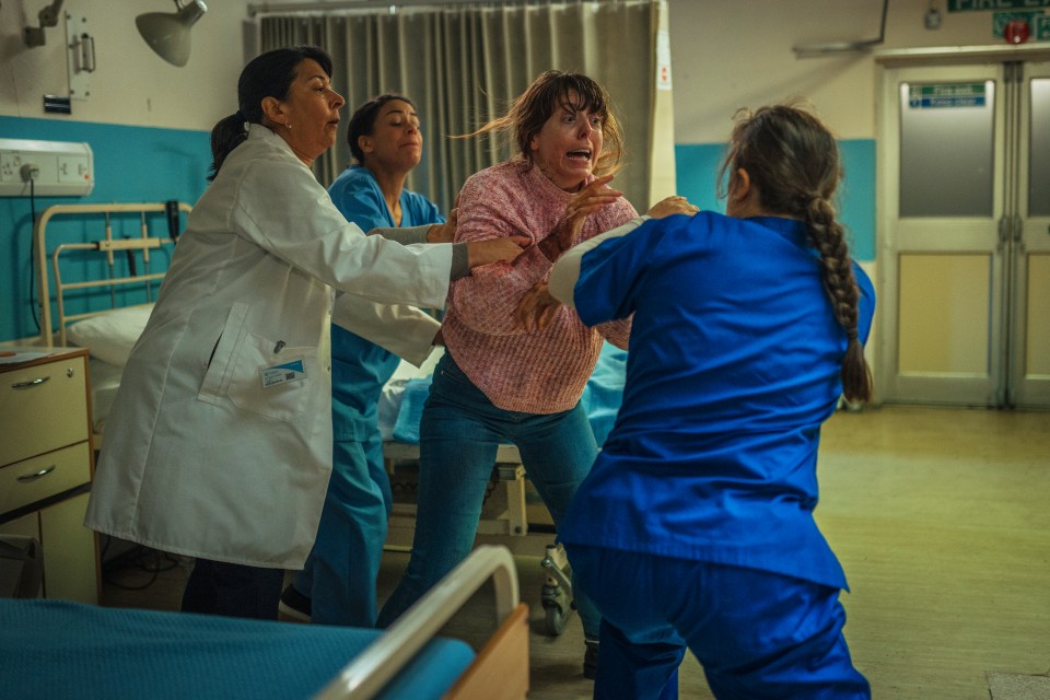 a woman in a pink sweater is being held by a doctor and two nurses