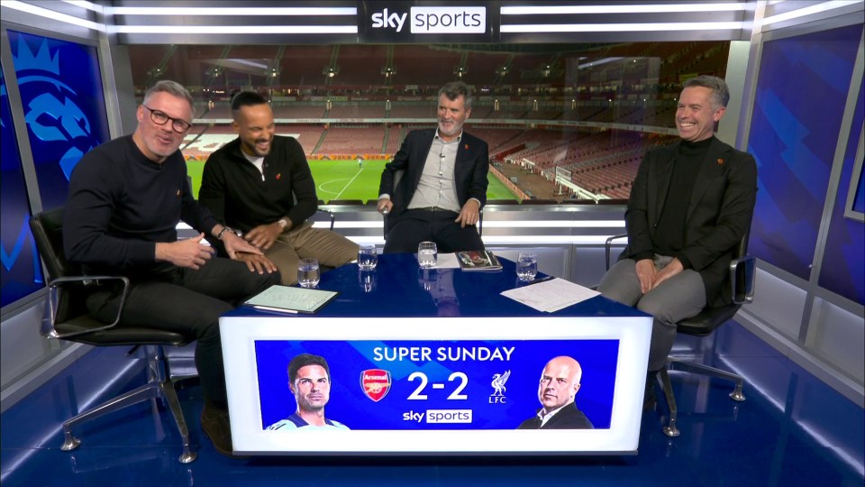 four men sit at a table in front of a sky sports sign