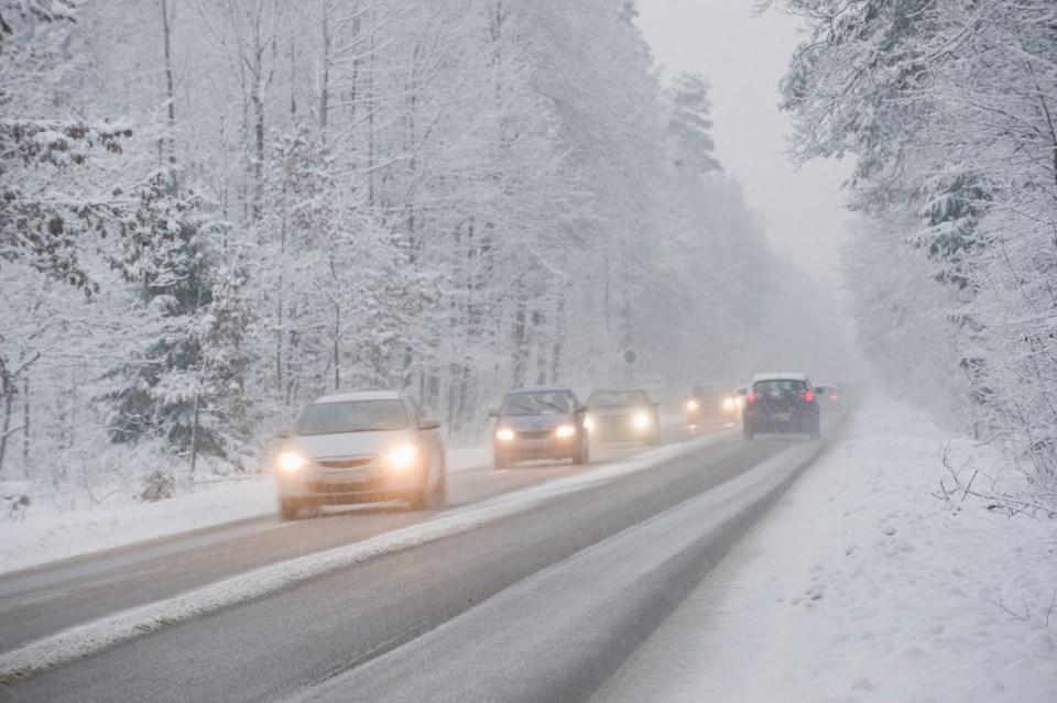 several cars are driving down a snowy road