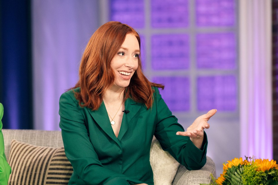 a woman with red hair is sitting on a couch and smiling