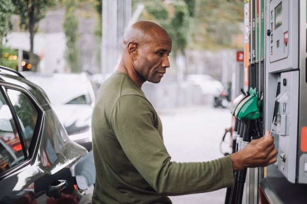 a man pumps gas into his car at a gas station