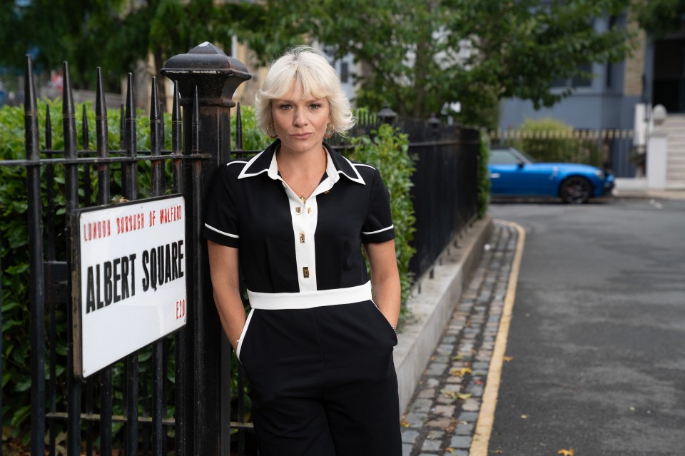 a woman stands in front of a sign that says albert square