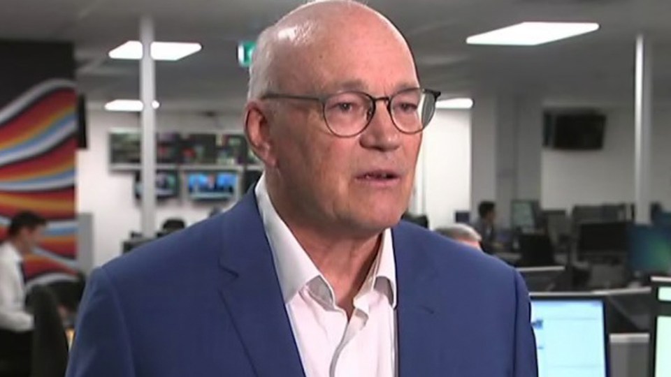 a bald man wearing glasses and a blue suit is standing in an office .