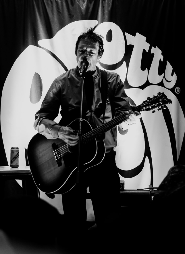 a man playing a guitar in front of a pitty logo