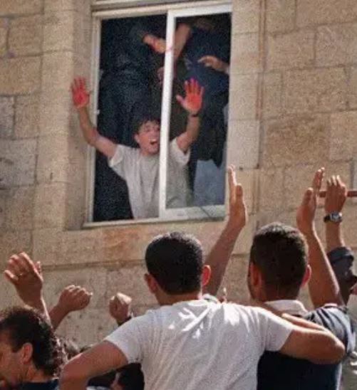 a group of people are standing around a window with their hands in the air .