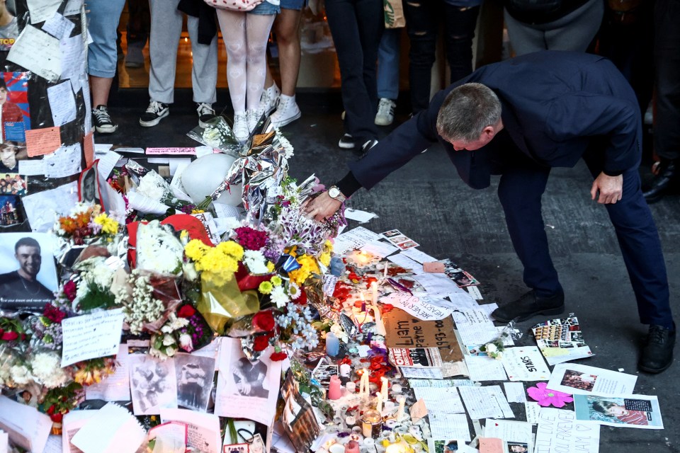 Geoff bends down to read some of the tributes left to his son