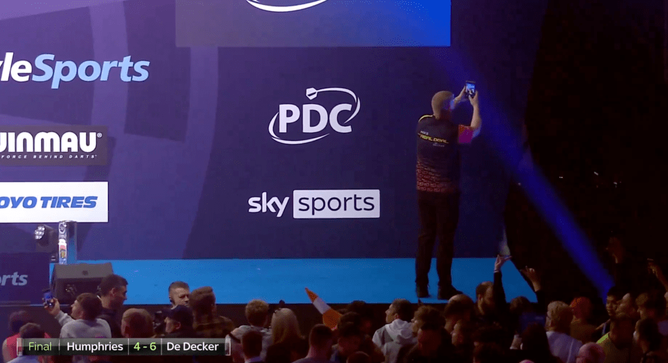 a man stands in front of a sky sports sign