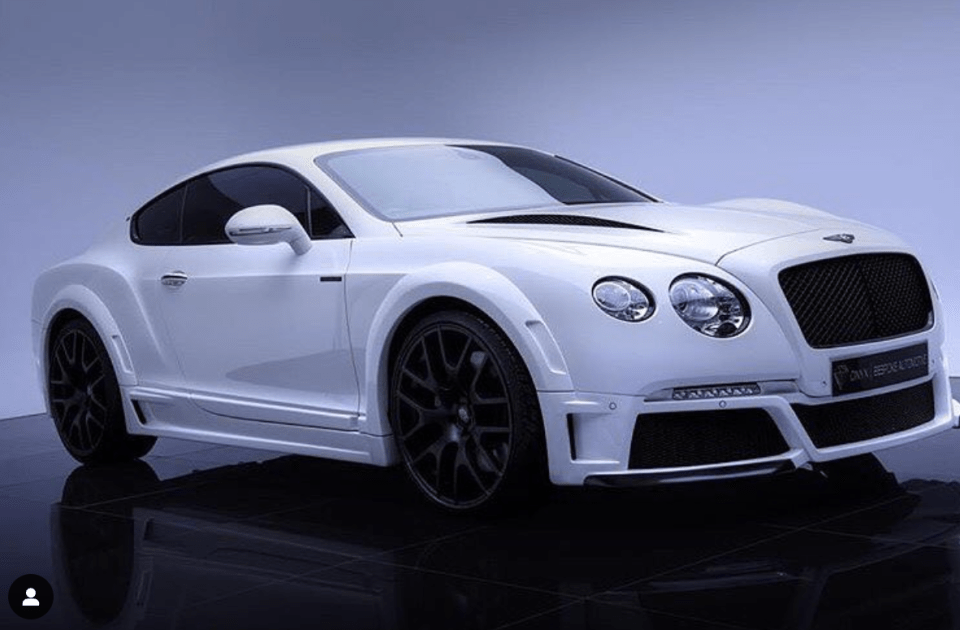 a white bentley is sitting on a black floor