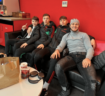 a group of young men are sitting on a couch and one of them is wearing an adidas jacket