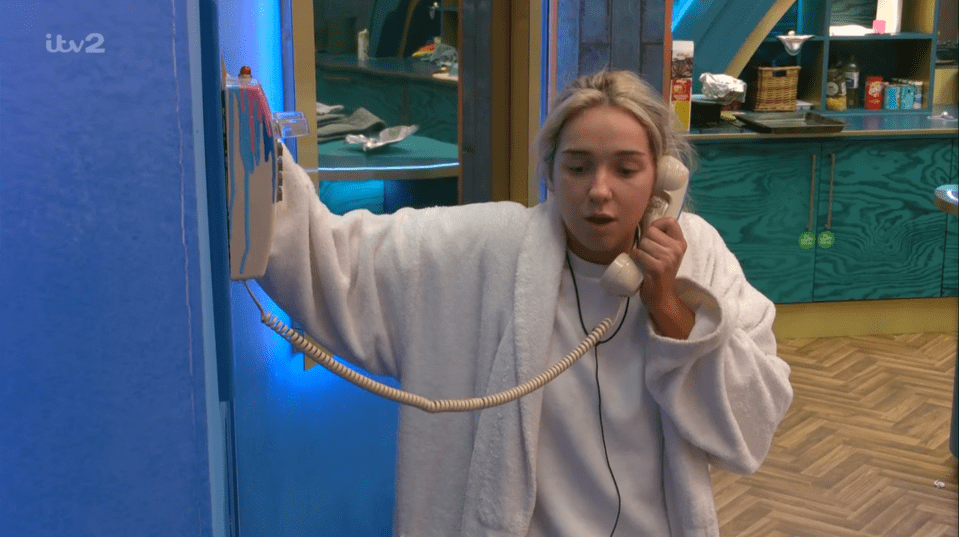 a woman in a bathrobe is talking on a phone with itv2 written on the bottom