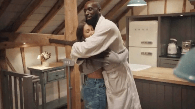 a man in a robe is hugging a woman in a kitchen .