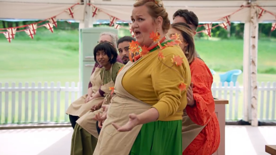 a woman in a yellow sweater is standing in front of a group of people